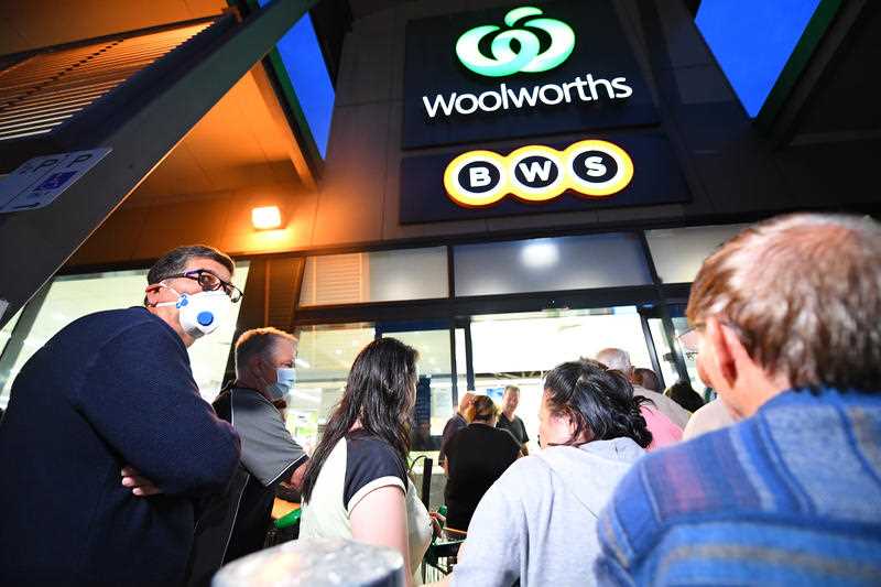 People are seen waiting in line outside a Woolworths supermarket in Coburg, Melbourne.