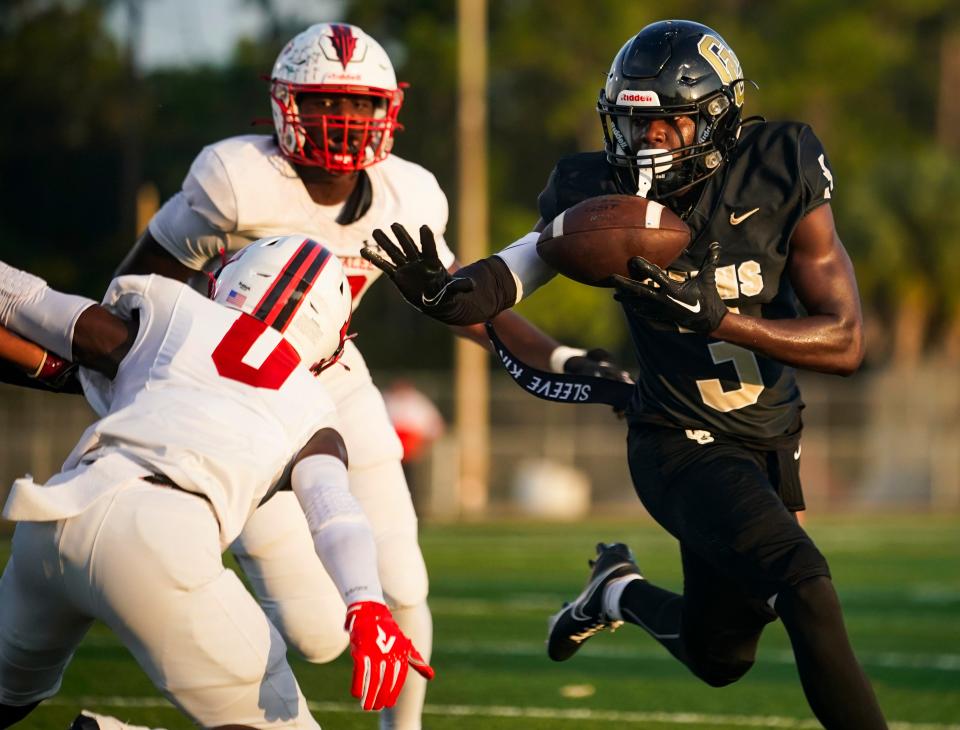 Golden Gate Titans running back John Lee Honorat (3) bobbles the ball while trying to stiff arm an Immokalee Indians defender during the first quarter of a game at Golden Gate High School in Naples on Friday, Sept. 1, 2023.