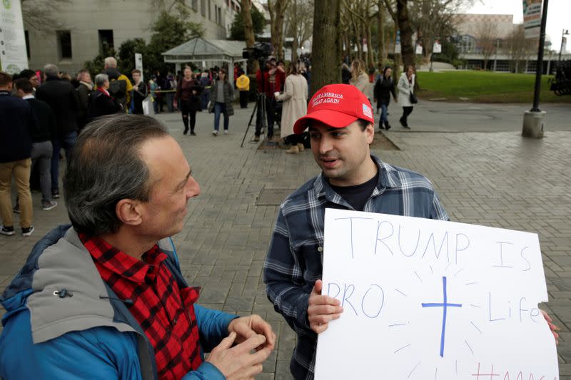 Wayne Miller (L) of Seattle engages Trump supporter Thomas Hager of Seattle in a political discussion as supporters line up at a rally for U.S. Democratic 2020 presidential candidate Senator Elizabeth Warren at the Seattle Center Armory in Seattle