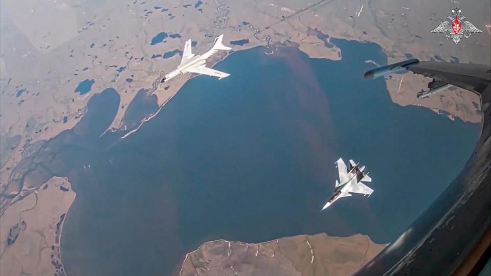 A H-6K long-range bomber of the Chinese air force, upper left, is seen escorted by a Su-30 fighter of the Russian air force during a joint Russia-China air patrol (Russian Defense Ministry Press Service)