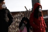 People wearing face masks walk along a street, as the country is hit by an outbreak of the new coronavirus, on outskirts of Beijing