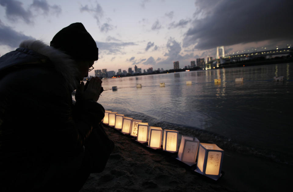 A man prays beside lanterns placed at the waterfront in Tokyo Bay to mark the first anniversary of the earthquake and tsunami which devastated northeast Japan, in Tokyo, Sunday, March 11, 2012. People across Japan prayed and stood in silence on Sunday to remember the massive disaster that struck the nation one year ago, killing just over 19,000 people and unleashing the world's worst nuclear crisis in a quarter century. (AP Photo/Greg Baker)