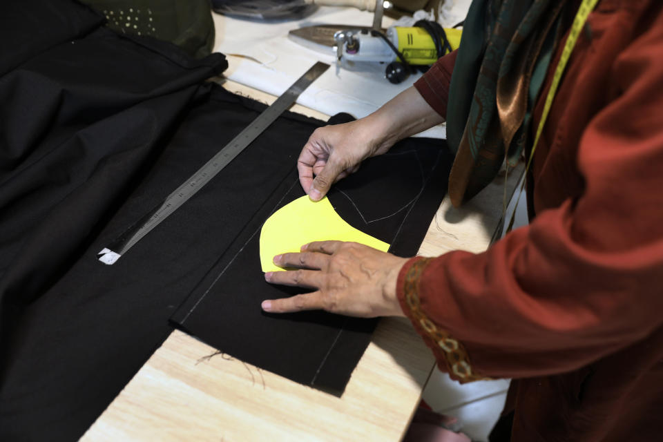 Fakhri Hashemian cuts fabric to sew a protective face mask at a workshop of Bavar charity in Tehran, Iran, Monday, Nov. 23, 2020. As the coronavirus pandemic ravages Iran, a women’s group hopes to empower its members by helping them make and sell face masks. (AP Photo/Vahid Salemi)