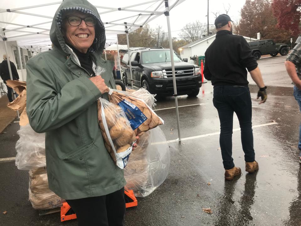 Janet Milne grabs two bags of potatoes for the Thanksgiving distribution at The Well in Spring Hill on Sunday.