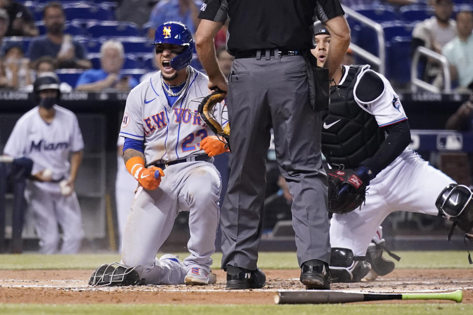 New York Mets' Javier Baez, left, reacts after scoring past Miami Marlins catcher Alex Jackson, right, during the second inning of a baseball game, Wednesday, Aug. 4, 2021, in Miami. (AP Photo/Lynne Sladky)