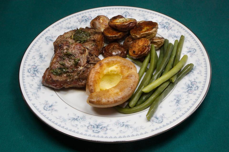 This meal inspired by memories of English pubs features Yorkshire Pudding, at front, accompanied clockwise by lamb chops topped with Easy Real British Mint Sauce, Crispy Roast Potatoes and green beans.