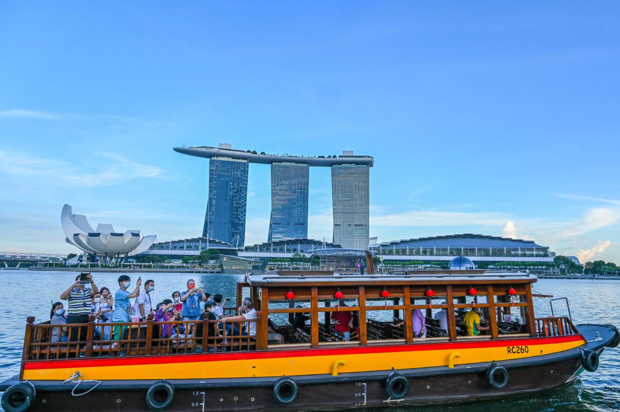 In this photograph taken on February 18, 2022, people take a boat tour before the Marina Bay Sands hotel and resort in Singapore. - Rivals Singapore and Hong Kong have become pandemic polar opposites, the former opting to live with the coronavirus and reopen to the world while the latter doubles down on zero-Covid and its international isolation. - To go with AFP story Health-virus-Hong Kong-China-Singapore, FOCUS by Holmes Chan with Catherine Lai in Singapore (Photo by Roslan RAHMAN / AFP) / To go with AFP story Health-virus-Hong Kong-China-Singapore, FOCUS by Holmes Chan with Catherine Lai in Singapore (Photo by ROSLAN RAHMAN/AFP via Getty Images)