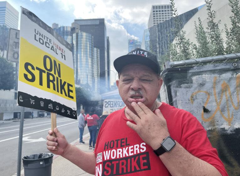 "Cristobal Guardado, 63, a cook at the L.A. Grand hotel, shows a Unite Here Local 11 employee Maria Hernandez a cut in his mouth. Guardado is among four people who allege a security guard assaulted them while they were picketing outside the hotel Friday morning Oct. 27 2023. Suhauna Hussain / Los Angeles Times