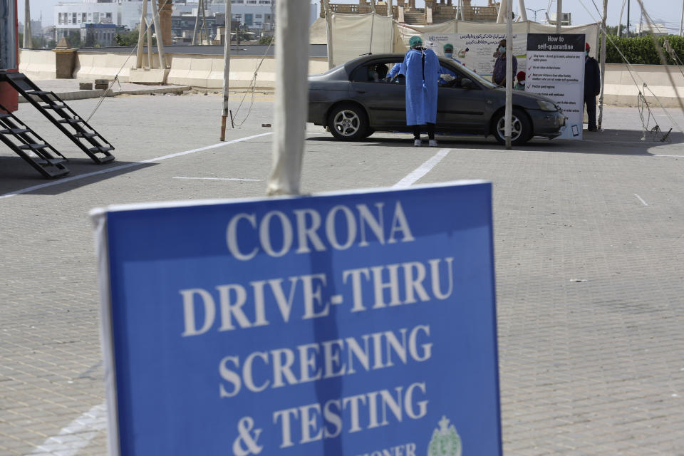 Health workers collect a specimen at a drive-thru testing and screening facility for the coronavirus, in Karachi, Pakistan, Monday, April 6, 2020. Authorities in Pakistan's Sindh province established the first ever drive-thru coronavirus testing facility in Pakistan as part of to control the spread of pandemic coronavirus in the province. (AP Photo/Fareed Khan)