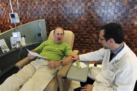 Dr. Antoni Ribas speaks with cancer patient Stew Scannell before Scannell receives an intravenous dose of lambrolizumab during a promising cancer treatment clinical trial at UCLA Medical Center in Los Angeles, California in this August 19, 2013 file picture. REUTERS/David McNew