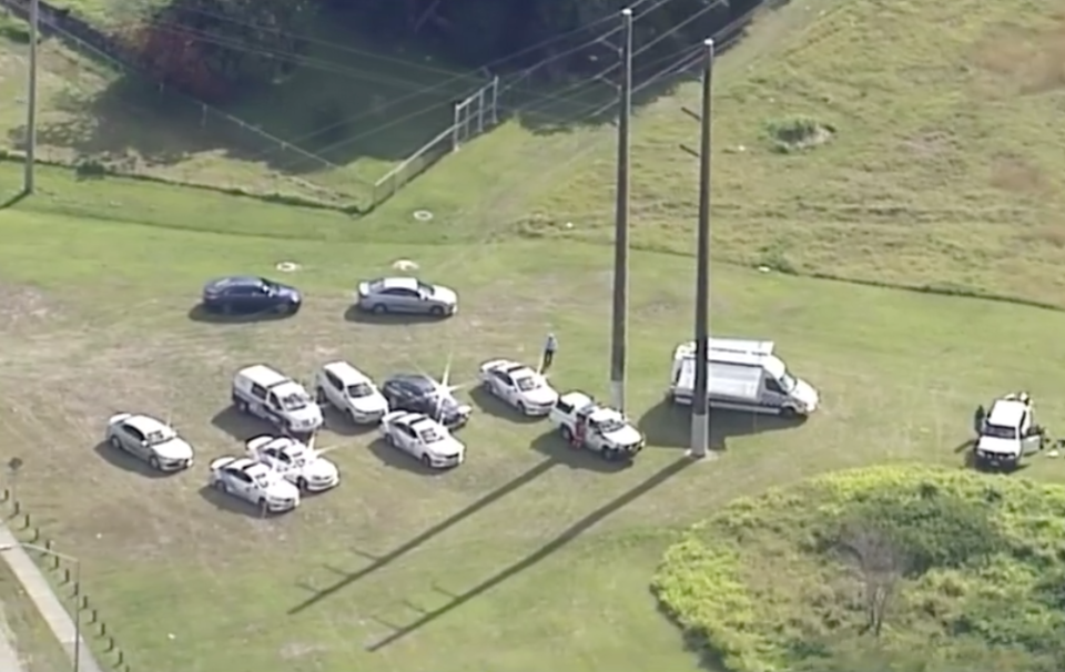 Aerial view of police vehicles and officers at a clearing near Slacks Creek, Brisbane, where a body was found.