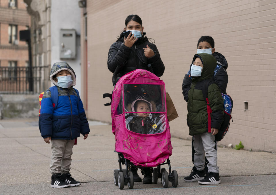 A woman and her children walk to P.S. 134 Henrietta Szold Elementary School, Monday, Dec. 7, 2020, in New York. Public schools reopened for in-school learning Monday after being closed since mid-November. (AP Photo/Mark Lennihan)