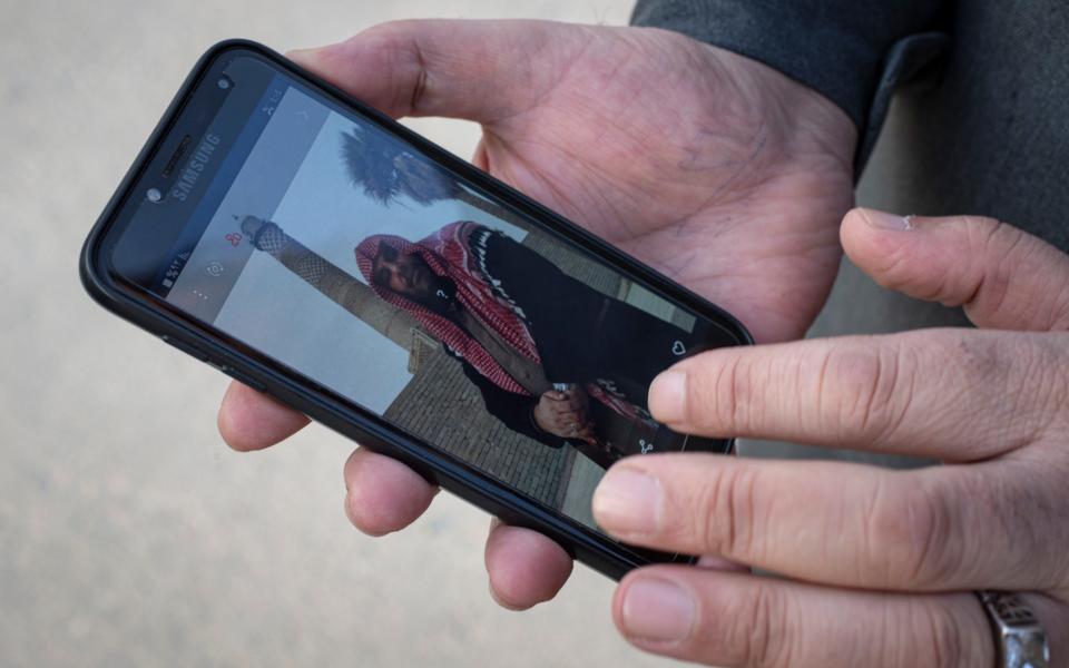 Imad Zaki, 52, the muezzin of the Al Nuri mosque, shows a picture of himself in front of the famous leaning minaret before it was destroyed