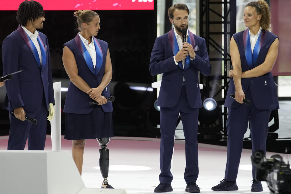 From left, French athletes Arnaud Assoumani, Pauline Deroulede, Romain Cannone, and Melina Robert-Michon stand on stage as they wear the French team uniforms for the Paris 2024 Olympic Games opening ceremony, Wednesday, April 17, 2024 at the Grand Palais Ephemere venue in Paris. (AP Photo/Christophe Ena)