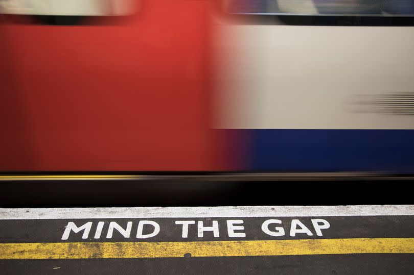 A Mind the Gap sign on the floor as a Tube train passes through a station