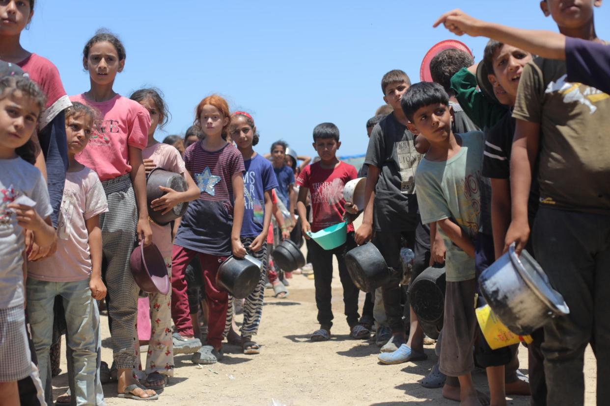 <span>Palestinians, including children, line up for aid in Deir al-Balah amid Ongoing Israeli attacks on Gaza.</span><span>Photograph: Anadolu/Getty Images</span>