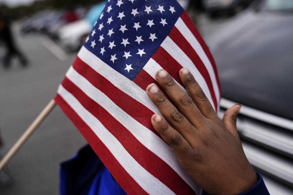 FILE - In this Nov. 15, 2020, fie photo a young child holds an American flag as Georgia Democratic candidate for U.S. Senate Raphael Warnock speaks during a campaign rally in Marietta, Ga. (AP Photo/Brynn Anderson, File)