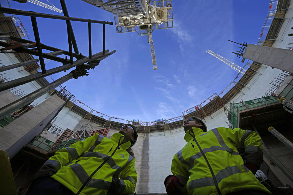 Employees look up at the construction site of Hinkley Point C nuclear power station in Somerset, England, Tuesday, Oct. 11, 2022. Sites like Hinkley have become integral to the U.K. government’s “net zero” by 2050 strategy. (AP Photo/Kin Cheung)