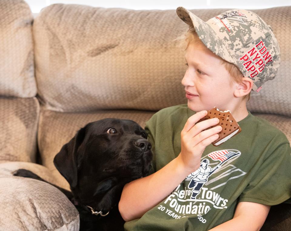 Service dog Bloom eyes the ice cream sandwich of Lism Bowman during the unveiling of the mortgage-free home donated by Tunnels to Towers Foundation, Wednesday, June 21, 2023, in Oxford, Ind. 