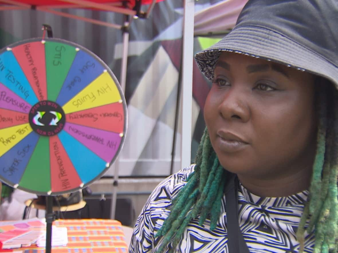 Natasha Lawrence, a community health worker for Women's Health in Women's Hands Community Health Centre, stands near the centre's booth at Blockobana. The booth offered free rapid anonymous HIV testing on Sunday. (CBC - image credit)