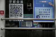 A temperature scanner stands near a display note showing a health check and travel QR codes at a closed fast-food restaurant in Beijing, Monday, Dec. 12, 2022. China will drop a travel tracing requirement as part of an uncertain exit from its strict "zero-COVID" policies that have elicited widespread dissatisfaction. (AP Photo/Andy Wong)