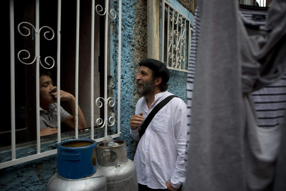 In this April 11, 2014 photo, "Safari in Tepito" director Daniel Gimenez Cacho, right, talks with a young resident through a window in the Tepito neighborhood of Mexico City. "I have liked this neighborhood since I was young and I was worried that a place I love so much, that to me represents the heart of Mexican identity, could be defined only by how many dead people there were, or how much cocaine was trafficked," said Gimenez, one of Mexico's best known actors who has starred in films by directors Pedro Almodovar and Alfonso Cuaron among others. (AP Photo/Rebecca Blackwell)