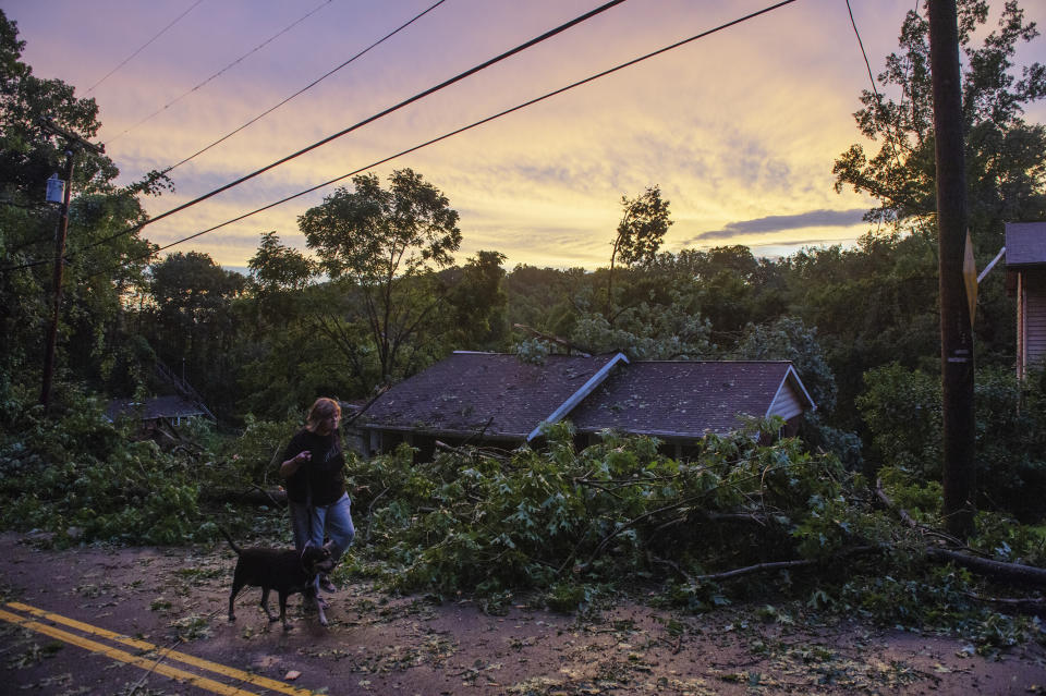 Rachel Trout walks her dog Lilly past a house partly destroyed by a falling tree after a suspected tornado tore through Charleston, W.Va., Monday, June 24, 2019. (Craig Hudson/Charleston Gazette-Mail via AP)