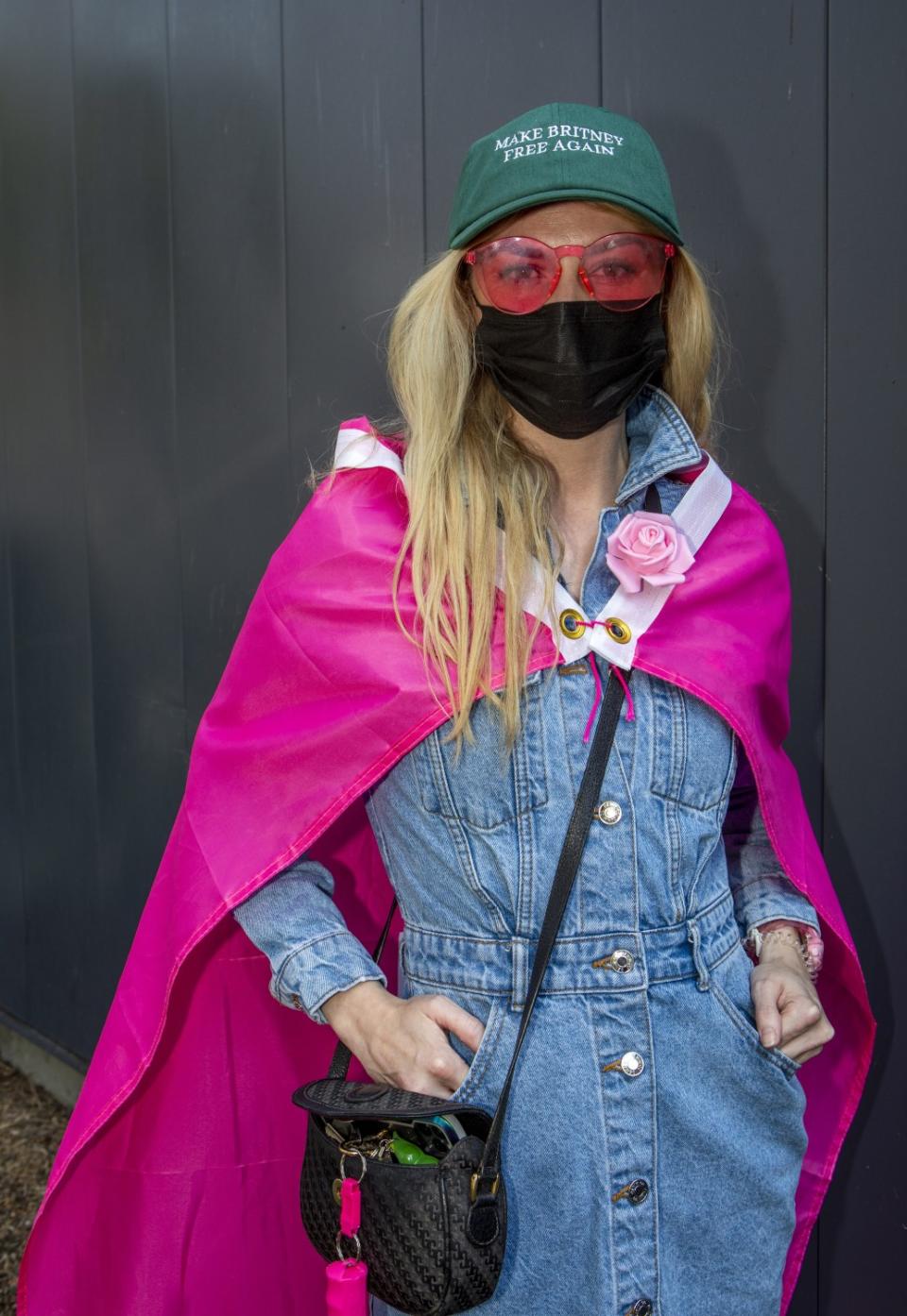 A woman wears a pink cape and hat that says "Make Britney free again"