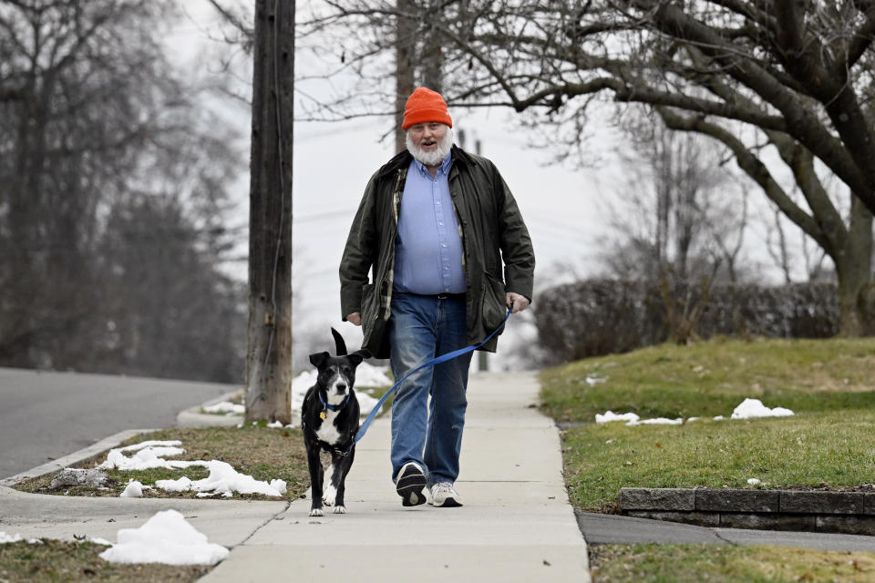 Casey Rosseau walks with his dog Darcy while listening to an e-book in West Hartford, Conn., Feb. 1, 2024. Rosseau, who estimates he reads about 200 books a year, said he'd like to see more regulation of what publishers can charge libraries. Libraries have been grappling with soaring costs of digital titles, both e-books and audio books, that libraries typically lease from publishers for a year or two, with limited usage. (AP Photo/Jessica Hill)