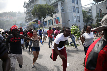 Protesters run away as Haitian National Police officers disperse them with tear gas during a march to demand an investigation into what they say is the alleged misuse of Venezuela-sponsored PetroCaribe funds, in Port-au-Prince, Haiti, October 17, 2018. REUTERS/Andres Martinez Casares