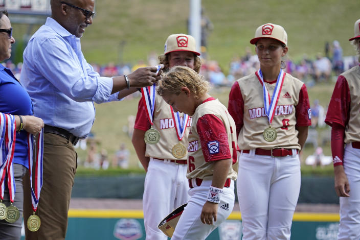 Santa Clara, Utah's Brogan Oliverson, center, receives a medal during player introductions before a baseball game against Nolensville, Tenn., at the Little League World Series in South Williamsport, Pa., Friday, Aug. 19, 2022. Brogan is taking the place of his brother Easton, who was injured when he fell out of his bunk. (AP Photo/Gene J. Puskar)