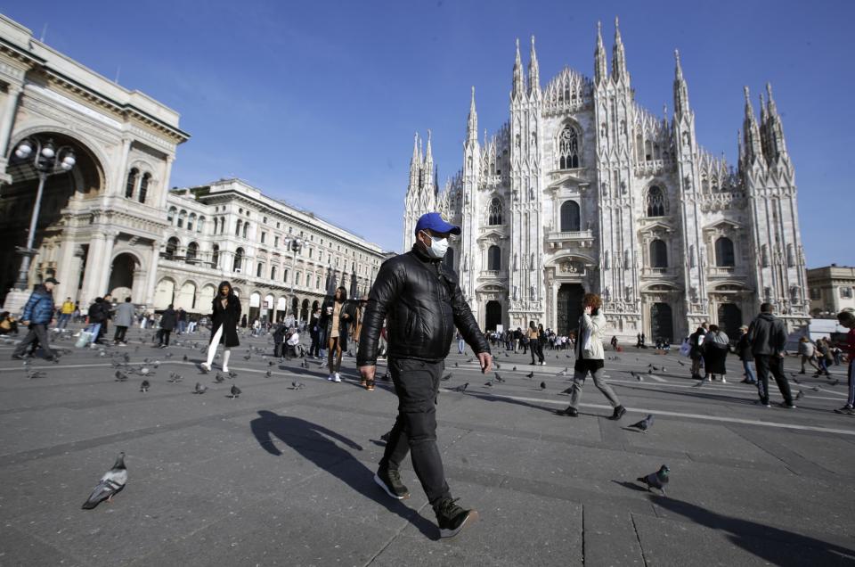 FILE - In this Feb. 24, 2020, file photo, a man wearing a sanitary mask walks past the Duomo gothic cathedral in Milan, Italy. As the coronavirus spreads around the world, International health authorities are hoping countries can learn a few lessons from China, namely, that quarantines can be effective and acting fast is crucial. On the other hand, the question before the world is to what extent it can and wants to replicate China’s draconian methods. (AP Photo/Luca Bruno, File)