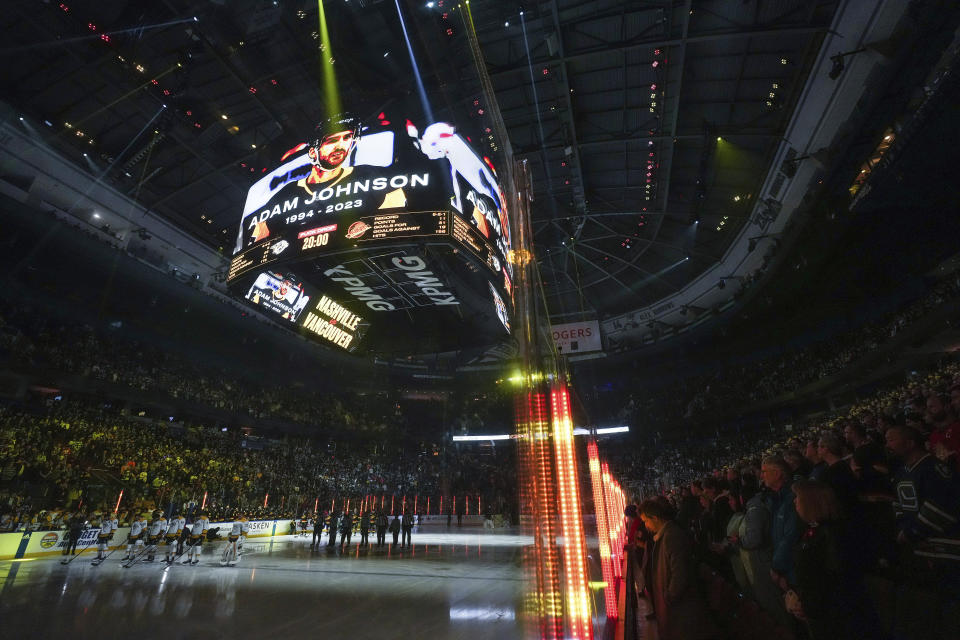 Nashville Predators and Vancouver Canucks players and spectators stand for a moment of silence for Adam Johnson, before an NHL hockey game Tuesday, Oct. 31, 2023, in Vancouver, British Columbia. Johnson died after a skate cut his neck during a game in England. (Darryl Dyck/The Canadian Press via AP)