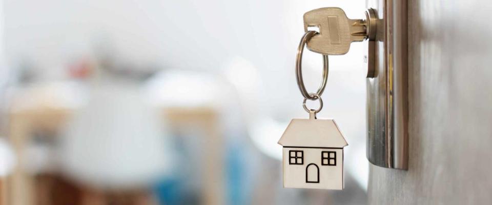 Key with keychain in a house shape in the door keyhole. Buy new home concept. Real estate market.