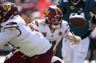 Washington Commanders quarterback Carson Wentz (11) looses the ball as he gets hit by Philadelphia Eagles defensive end Brandon Graham (55) during the first half of an NFL football game, Sunday, Sept. 25, 2022, in Landover, Md. (AP Photo/Alex Brandon)