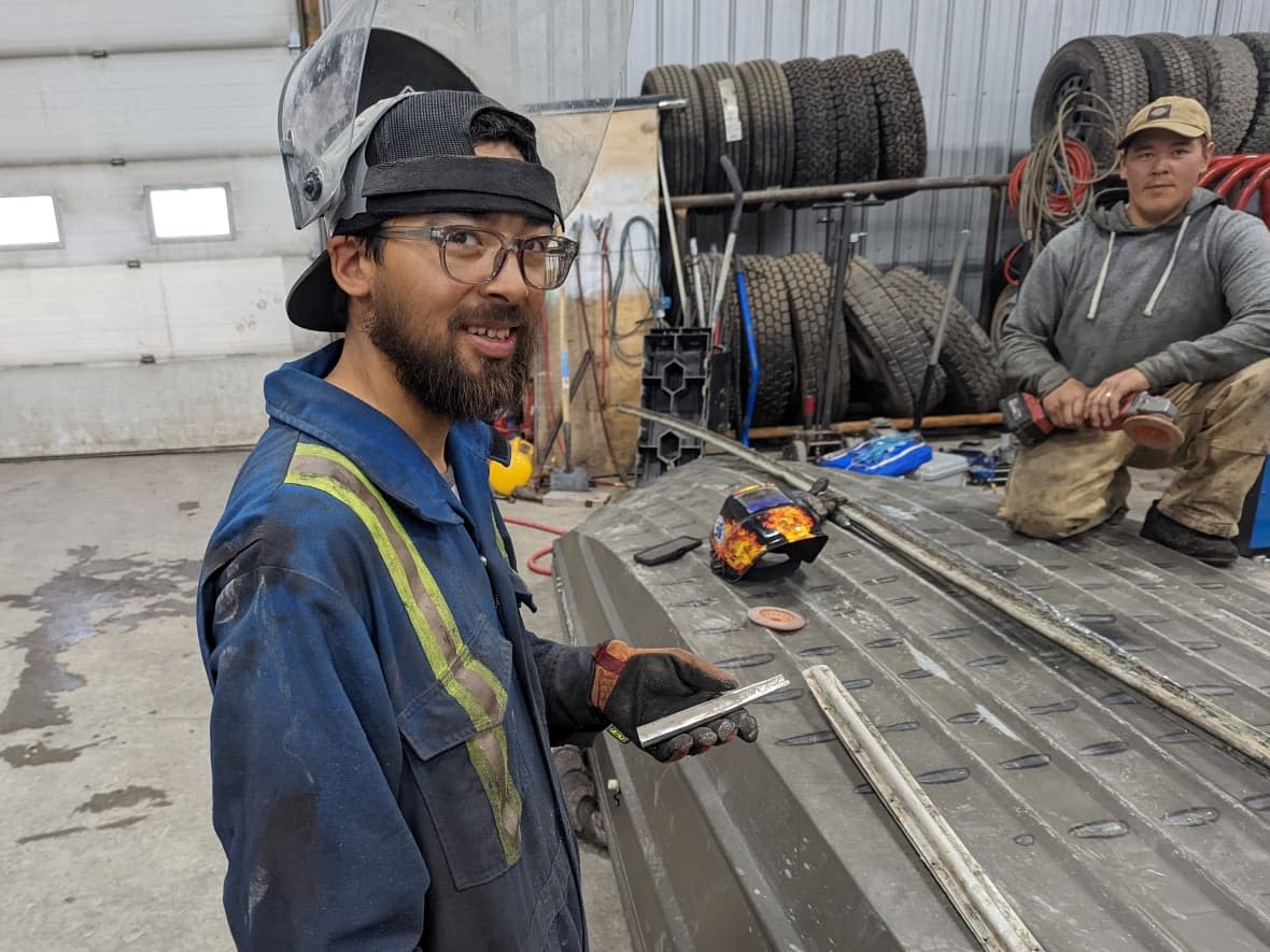 Myles Pedersen, centre, Kevin Ongahak, right, and Robin Paco Ilgok (not pictured) rebuilt the vessel of Robert Youens after the Texan arrived in Kugluktuk, Nunavut, with a 45-inch crack in his boat. (Robert Youens - image credit)