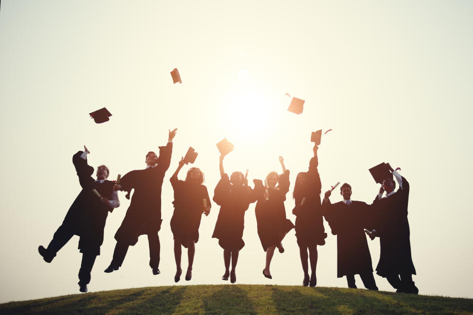 Students in robes throw their hats in the air.