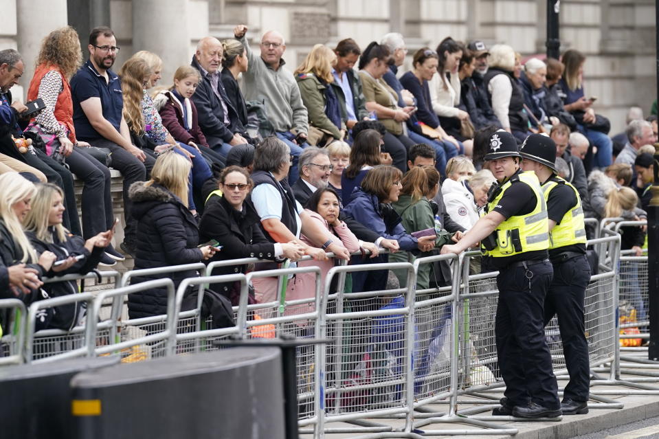 Varias personas esperan antes del paso del cortejo fúnebre de la reina Isabel II desde el Palacio de Buckingham a Westminster, en Westminster, en el centro de Londres, el 14 de septiembre de 2022. (Danny Lawson/PA vía AP)