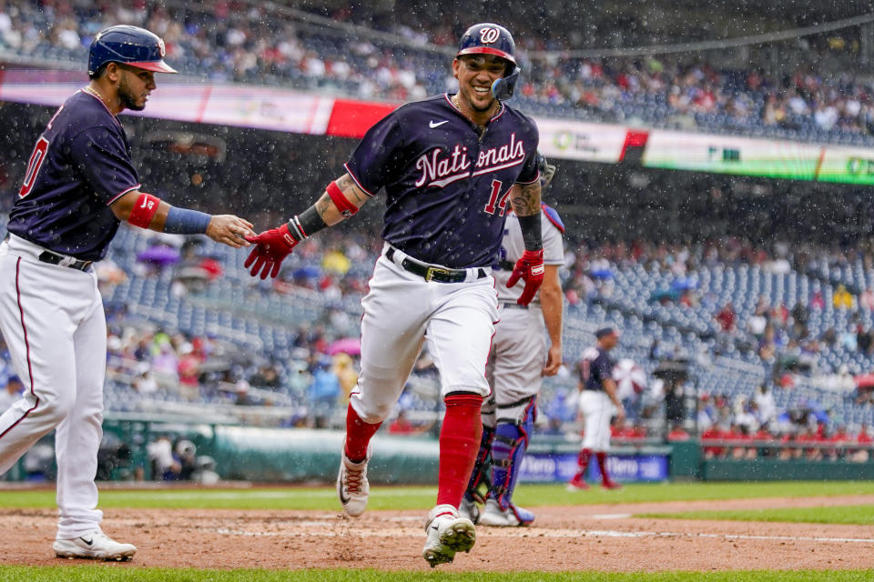 Washington Nationals' Keibert Ruiz, left, and Ildemaro Vargas (14) celebrate in the rain after they scored on a single hit by Drew Millas during the fourth inning of a baseball game against the Los Angeles Dodgers at Nationals Park, Sunday, Sept. 10, 2023, in Washington. (AP Photo/Andrew Harnik)