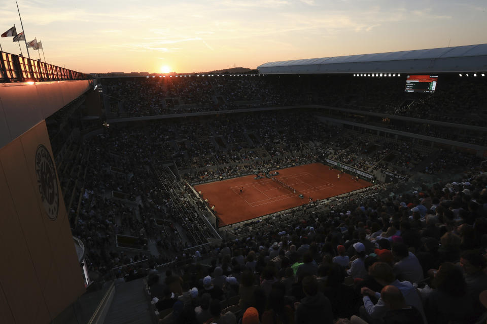 The sun sets over the court during the first round match of the French Open tennis tournament between France's Gael Monfils and Argentina's Sebastian Baez at the Roland Garros stadium in Paris, Tuesday, May 30, 2023. (AP Photo/Aurelien Morissard)