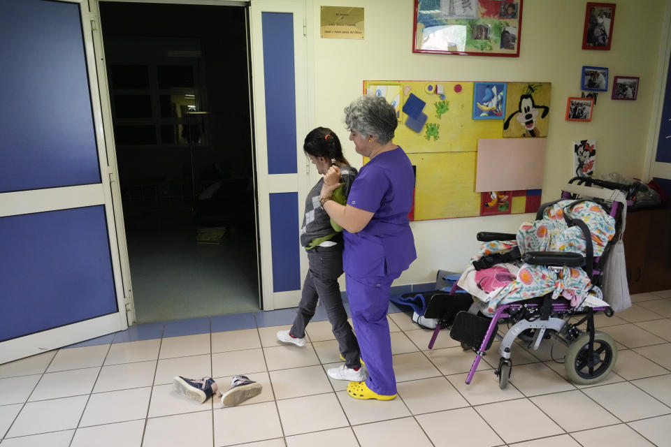 Lucia D'Avvento, left, is helped walking by Giulia Diffidenti inside the Chicco community of L'Arche, an International charity that helps people with intellectual disabilities, in Ciampino, near Rome, Wednesday, March 22, 2023. The findings of expert reports commissioned by L’Arche itself reveal that their founder, Jean Vanier, perverted Catholic doctrine to justify his own sexual compulsions and abuse women and that the movement he created had at its core a secret, a mystical-sexual “sect” founded for the precise purpose of hiding the sect’s deviant activities from church authorities. (AP Photo/Gregorio Borgia)