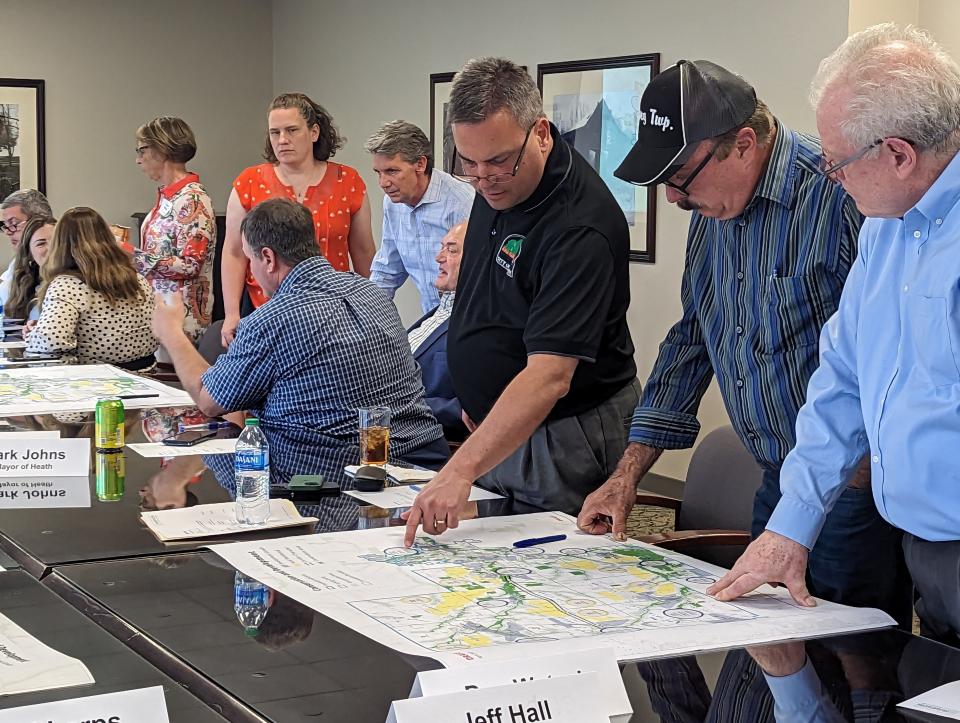 Newark Mayor Jeff Hall, from right, Jersey Township Trustee Dan Wetzel and Heath Mayor Mark Johns discuss a draft conservation and development map that depicts the order of magnitude of potential growth during one of Framework's monthly leadership meetings.