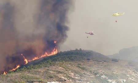 Firefighter helicopters fly over a wildfire engulfing a hillside in Benitatxell near Alicante, Spain September 5, 2016. REUTERS/Heino Kalis
