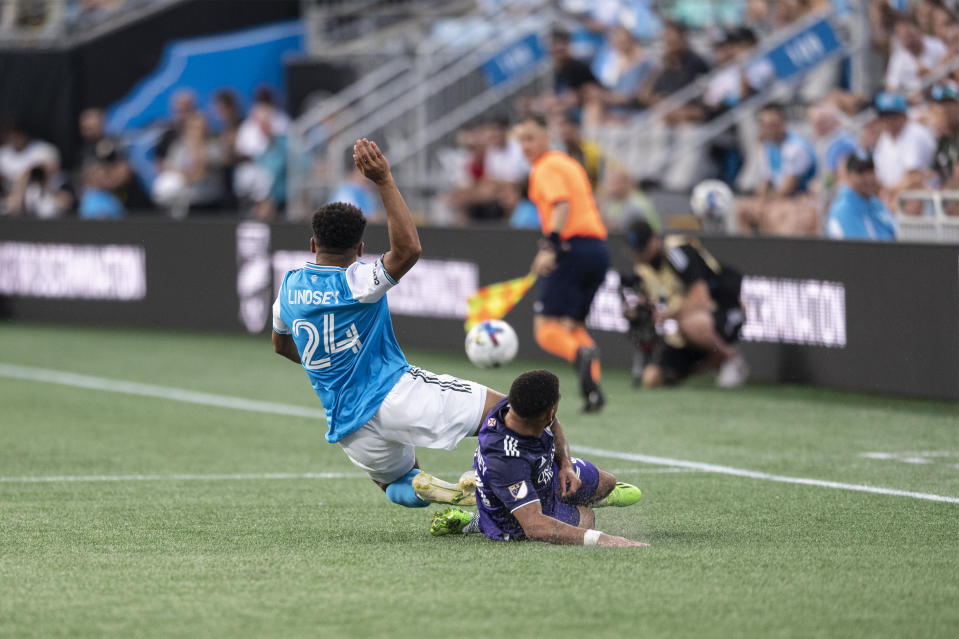 Orlando City midfielder Jake Mulraney slides under Charlotte FC defender Jaylin Lindsey (24) during the first half of an MLS soccer match, Sunday, Aug. 21, 2022, in Charlotte, N.C. (AP Photo/Matt Kelley)