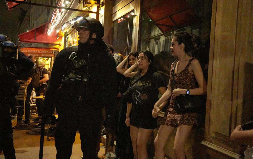 PARIS, FRANCE - JULY 1: Tourists are caught in a protest with anti-riot police officers pushing back protesters as thousands of supporters of the Popular Front (Front Populaire, left coalition) march in streets near Place de la RÃ©publique on July 1, 2024 in Paris, France. Today is the first round of legislative elections, with the second vote being held on July 7. The snap election was called by President Macron in response to his party's defeat in the European elections earlier this month. (Photo by Pierre Crom/Getty Images)