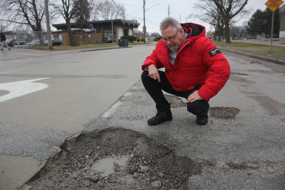 Paul Finlayson looking at a pothole in Windsor. He has filed a damage claim with the City of Windsor in the hopes of being reimbursed for damage to his car caused by a pothole.
