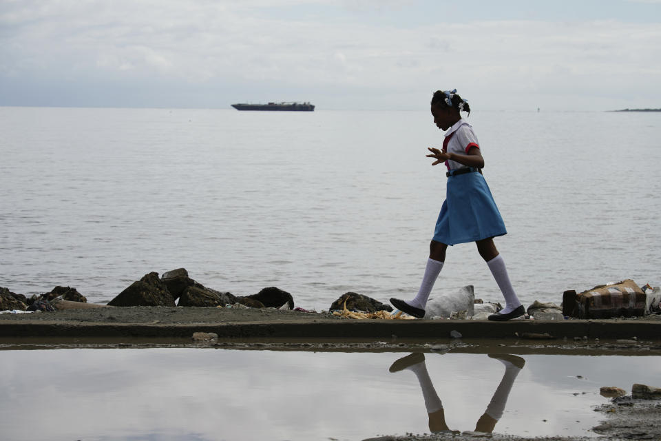 A girl walks alongside a body of water, in Cap-Haitien, Haiti, Wednesday, April 17, 2024. (AP Photo/Ramon Espinosa)