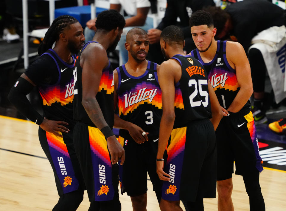 Chris Paul talks with Jae Crowder, Deandre Ayton, Mikal Bridges and Devin Booker in a huddle on the court.