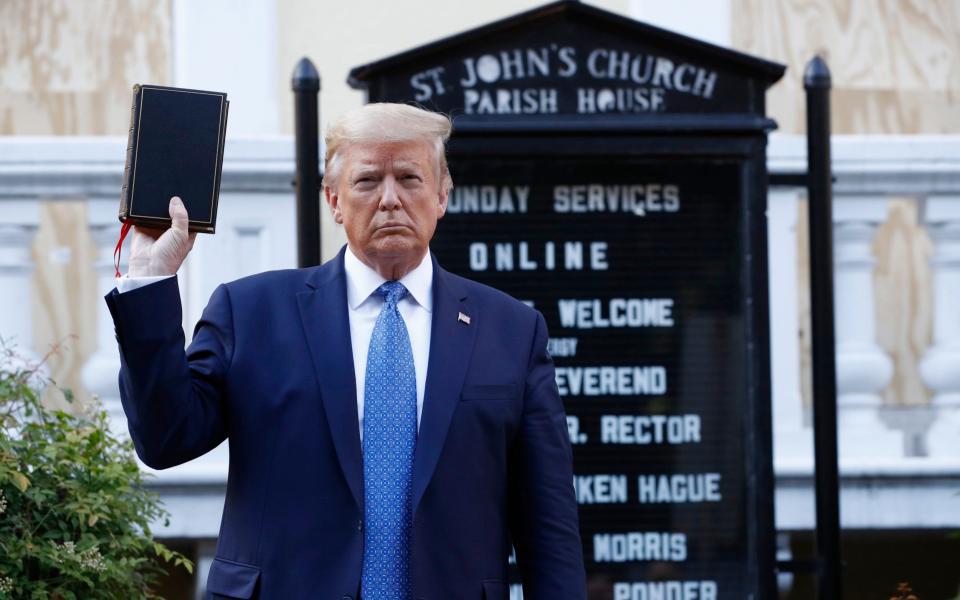 President Donald Trump holds a bible as he visits outside St. John's Church across Lafayette Park from the White House  - AP