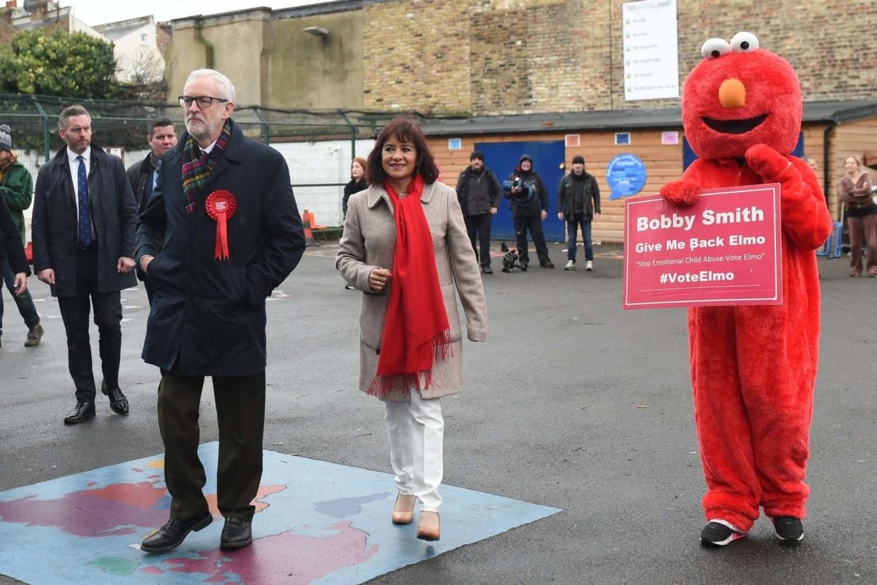 A protester dressed as Elmo tries approach Labour leader Jeremy Corbyn and his wife Laura Alvarez as they arrive to cast their votes: PA